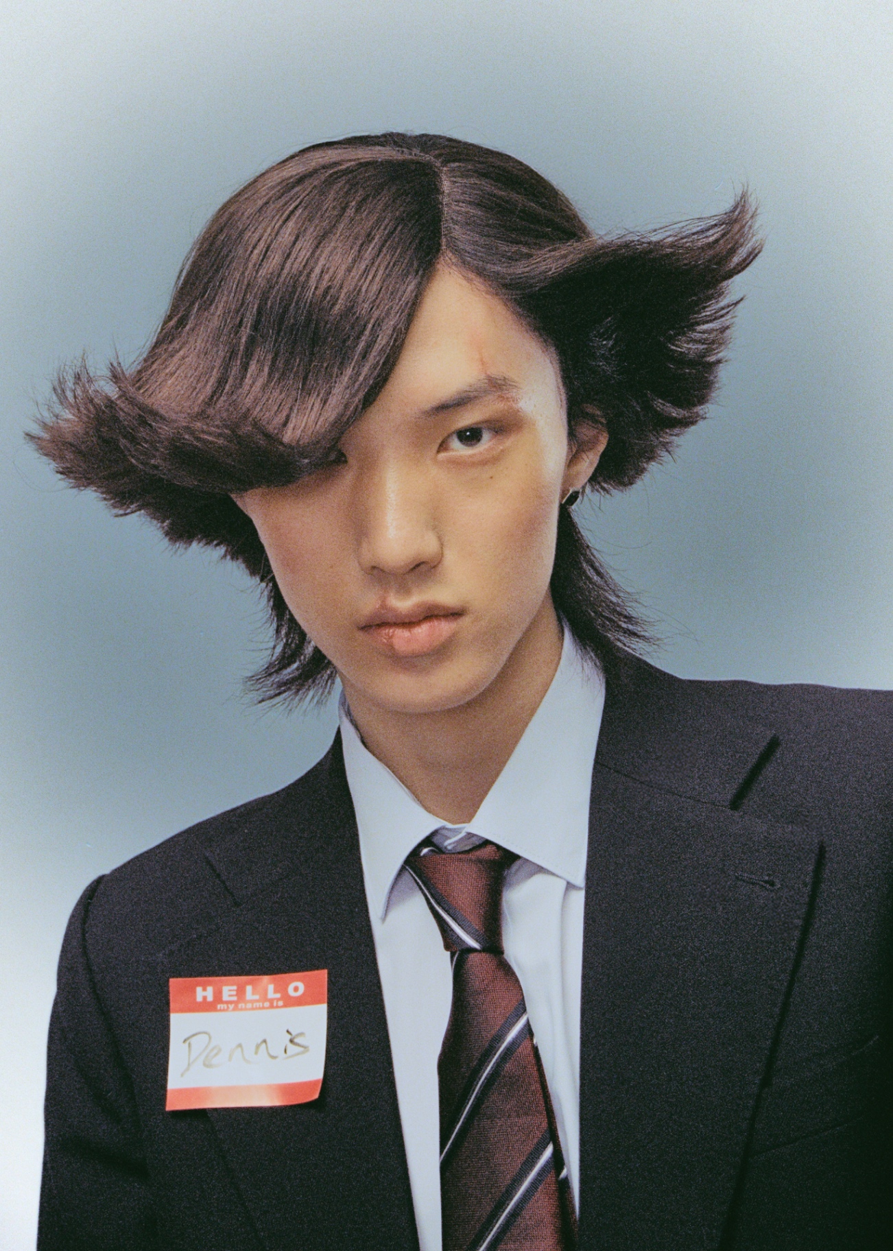 Studio portrait with sculpted dark hair and red tie