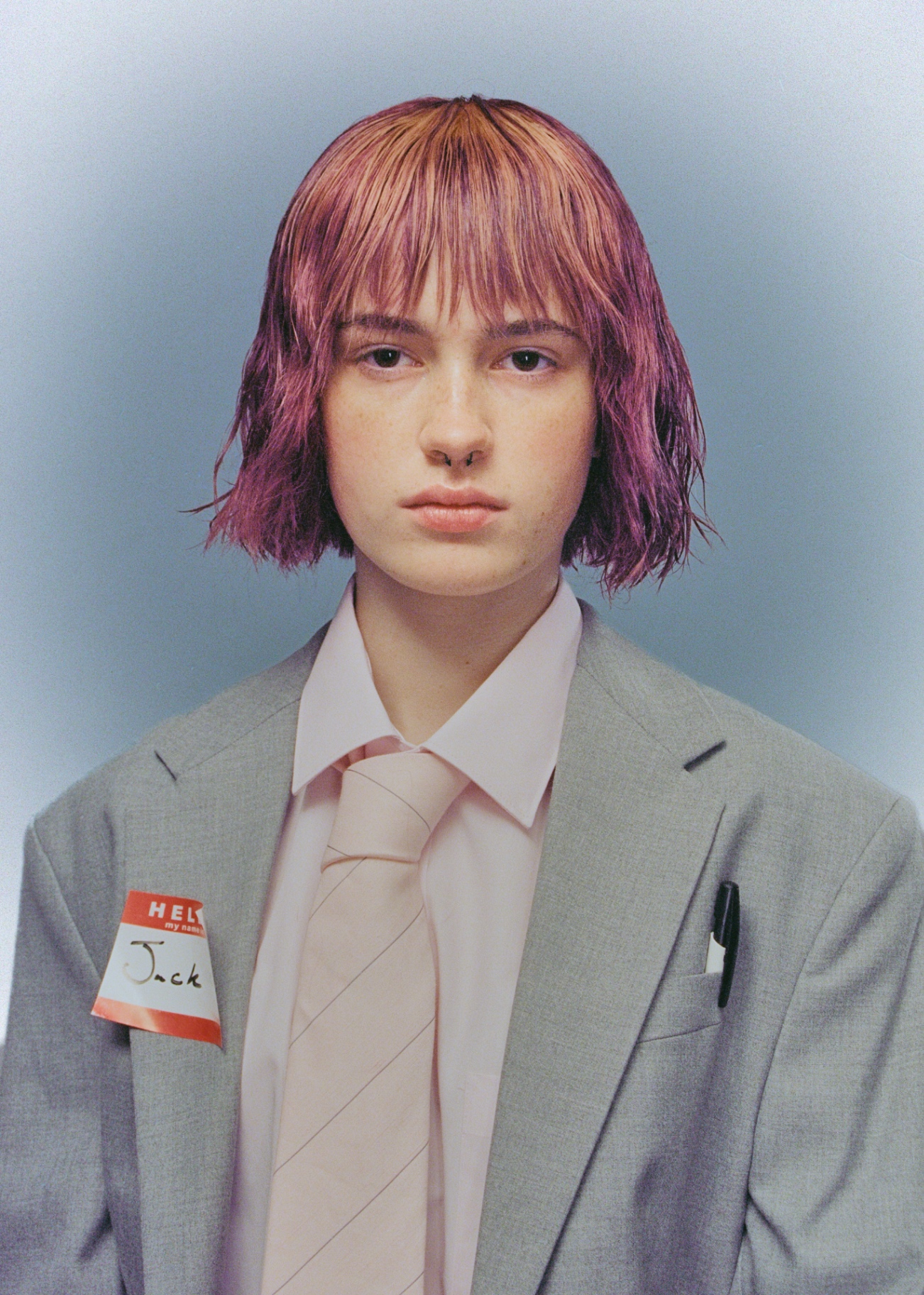 Pink-haired portrait in gray suit and pale tie