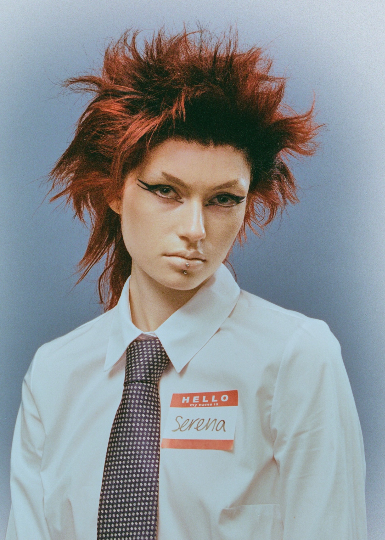 Portrait with vivid red textured hair and name tag