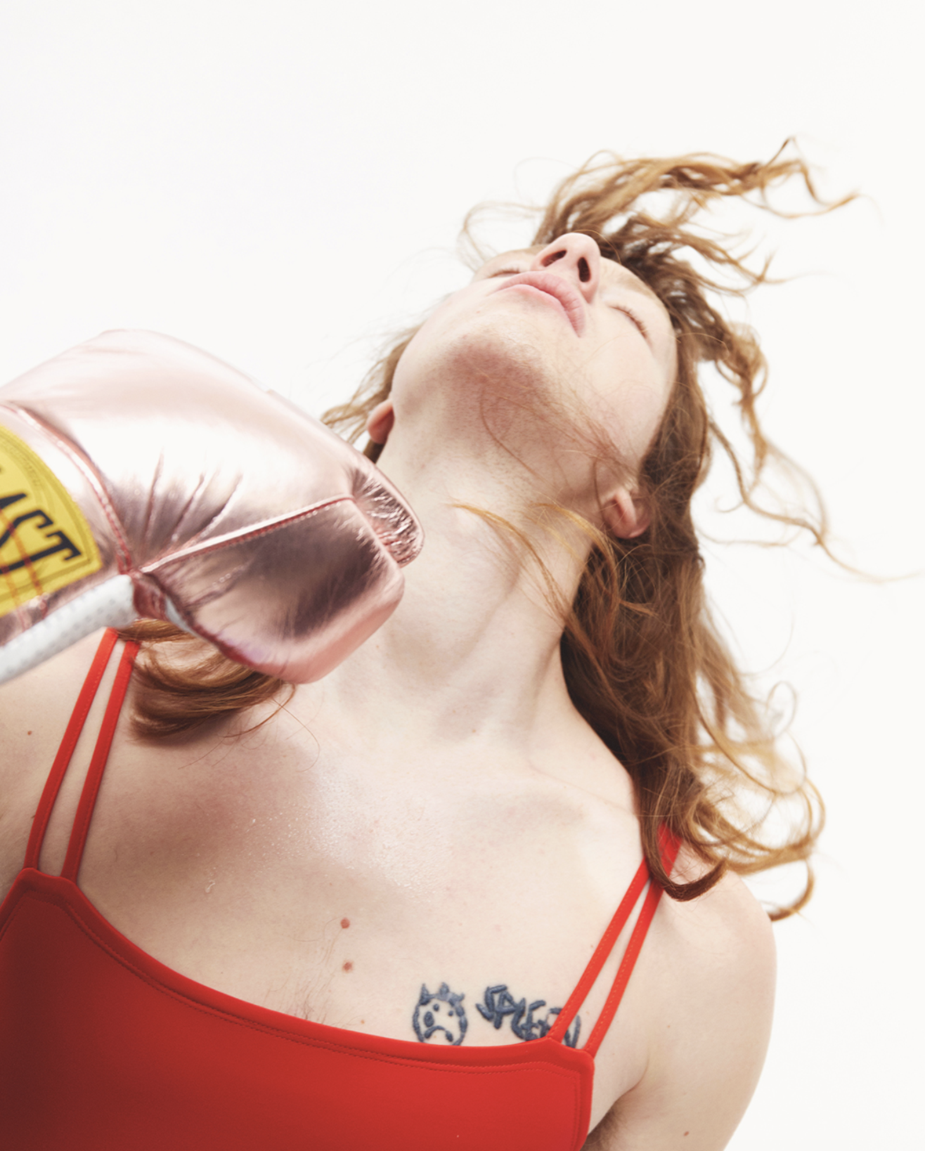 Boxing glove striking model's chin in red top